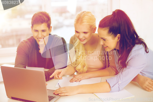 Image of three smiling students with laptop and notebooks