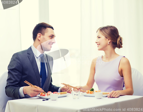 Image of smiling couple eating sushi at restaurant