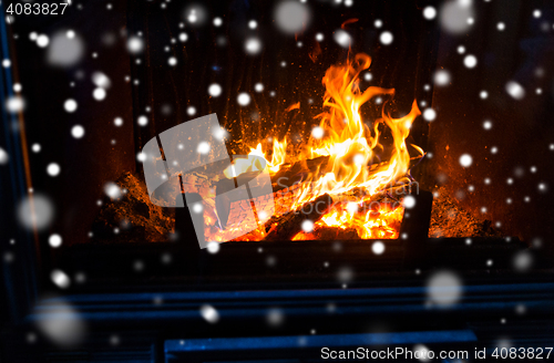 Image of close up of firewood burning in fireplace and snow
