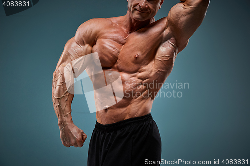 Image of torso of attractive male body builder on gray background.