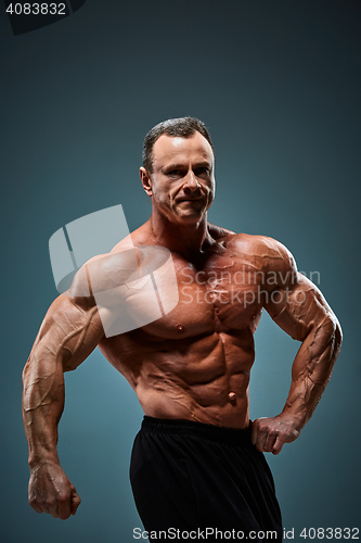 Image of torso of attractive male body builder on gray background.