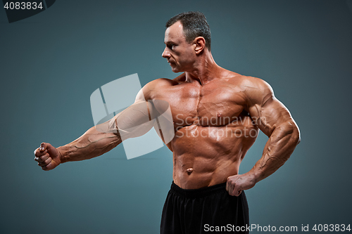 Image of torso of attractive male body builder on gray background.