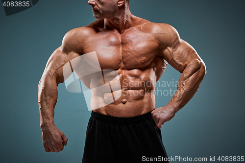 Image of torso of attractive male body builder on gray background.