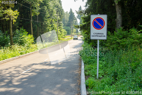 Image of Traffic sign \"No parking\" on the forest road on which the moving car