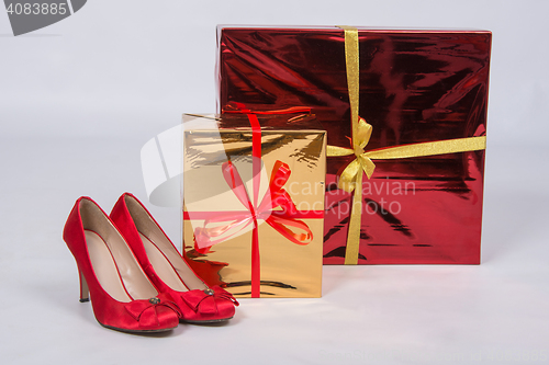 Image of Red female shoes with high heels, standing next to two boxes with gifts