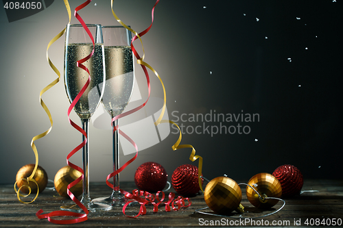 Image of Two glasses with sparkling champagne, snowflakes and Christmas balls