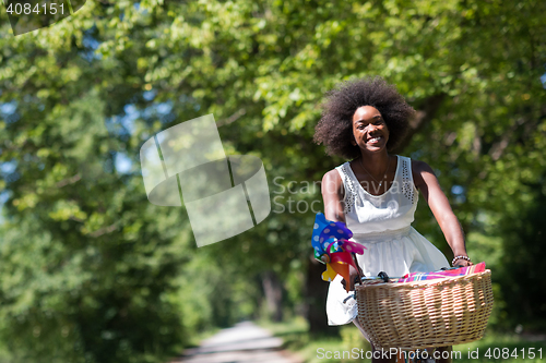 Image of pretty young african american woman riding a bike in forest