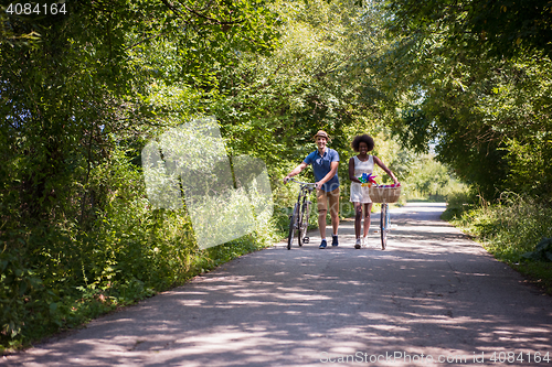 Image of Young multiethnic couple having a bike ride in nature