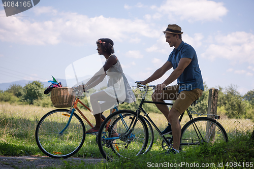 Image of Young multiethnic couple having a bike ride in nature