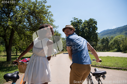 Image of Young multiethnic couple having a bike ride in nature