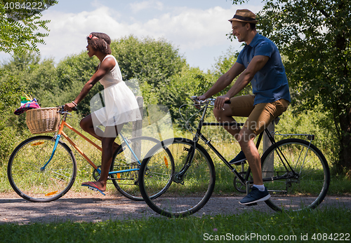 Image of Young multiethnic couple having a bike ride in nature