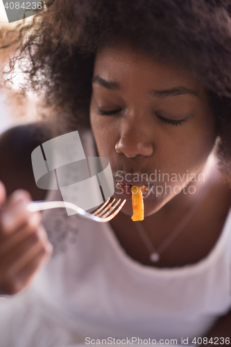 Image of a young African American woman eating pasta