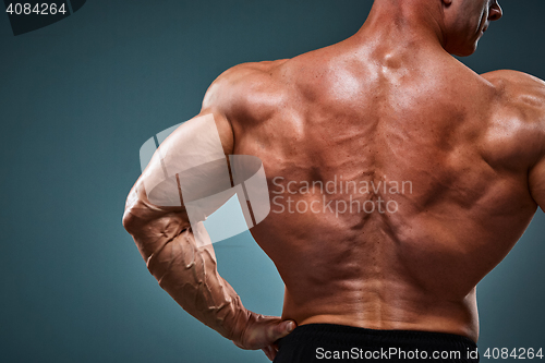 Image of torso of attractive male body builder on gray background.