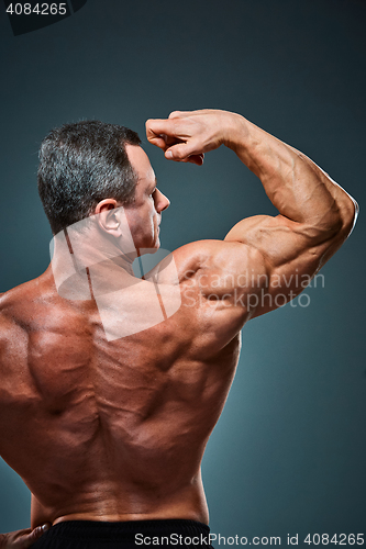 Image of torso of attractive male body builder on gray background.