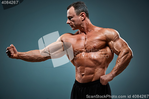 Image of torso of attractive male body builder on gray background.