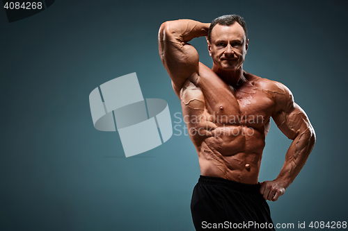 Image of torso of attractive male body builder on gray background.