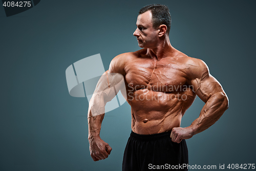 Image of torso of attractive male body builder on gray background.