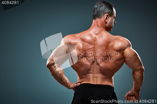 Image of torso of attractive male body builder on gray background.