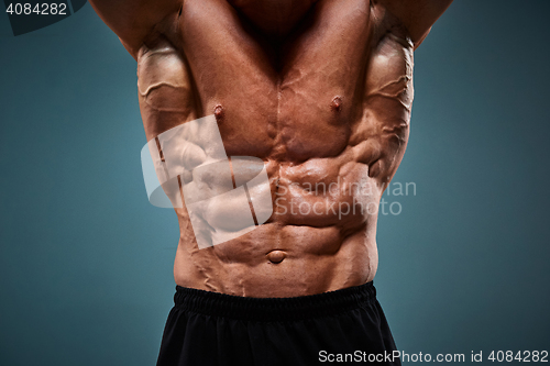 Image of torso of attractive male body builder on gray background.