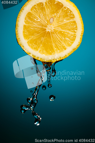 Image of Lemon slice and splash of juice isolated on blue background
