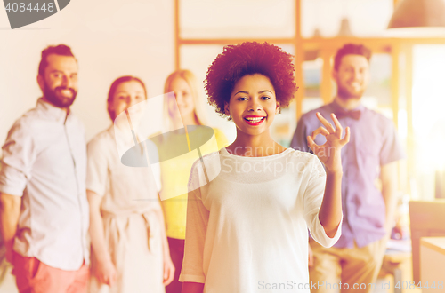 Image of happy woman showing ok over creative office team