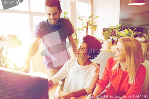 Image of happy creative team with computer in office