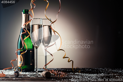 Image of Open bottle of champagne and two filled glasses with snowflakes