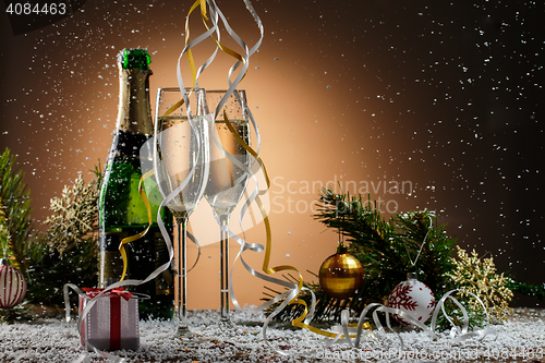 Image of Christmas composition with champagne, decorations and a snowfall