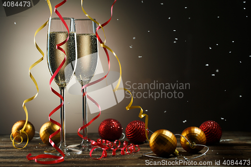 Image of Champagne glasses, snowflakes, Christmas red and yellow ball with ribbons