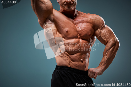 Image of torso of attractive male body builder on gray background.