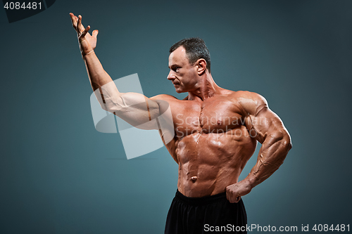 Image of torso of attractive male body builder on gray background.