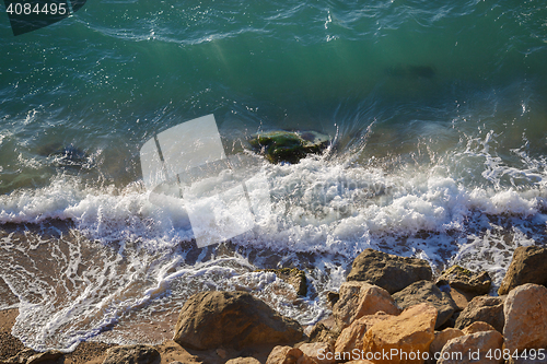 Image of Clear turquoise sea washes yellow stones on sunny summer day