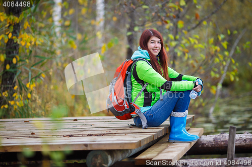 Image of Brunette with long hair and backpack tourist sits on bridge