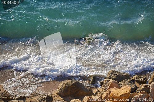 Image of Transparent waves crash on rocky shore