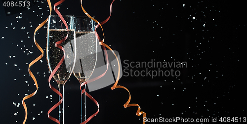 Image of Two glasses with champagne, decorative ribbons and snowflakes closeup