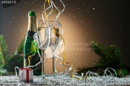Image of Two glasses of white champagne, open bottle and Christmas decorations