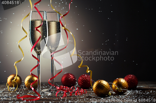 Image of Two champagne glasses decorated ribbons and toys. on black background