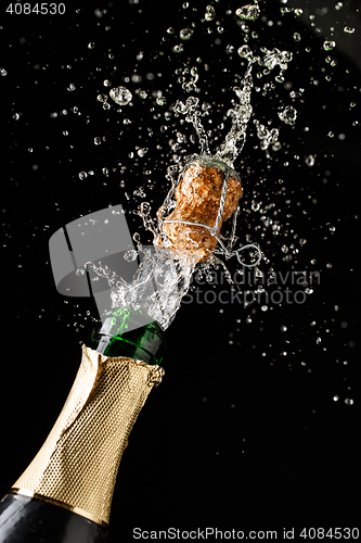 Image of Champagne cork popping and splashing on black background