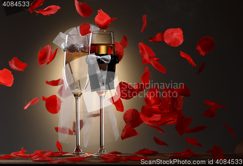 Image of Decorated wedding glasses with champagne and stream of rose petals