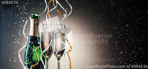 Image of Green bottle of champagne, wineglasses with silver and golden ribbons