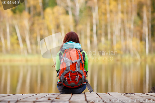 Image of Girls with backpack sitting back on wooden bridge