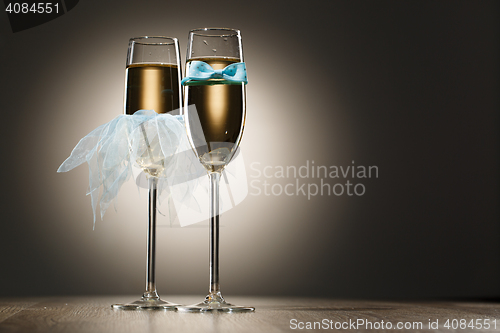 Image of Champagne glasses dressed in blue grooms bowtie and brides veil