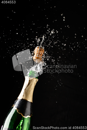 Image of Cork flies out of champagne bottle isolated on black background
