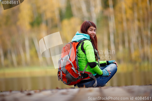 Image of Girl with backpack sitting on bridge at lake