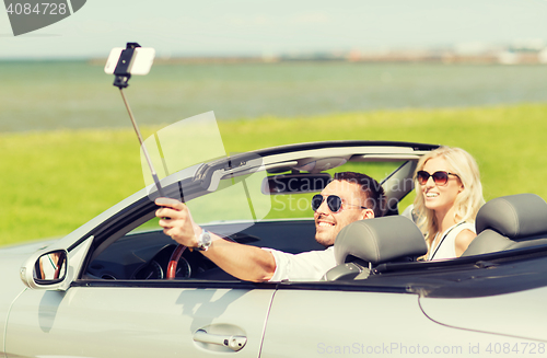 Image of happy couple in car taking selfie with smartphone