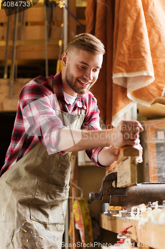 Image of carpenter working with plane and wood at workshop