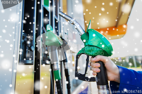 Image of close up of hand holding hose at gas station