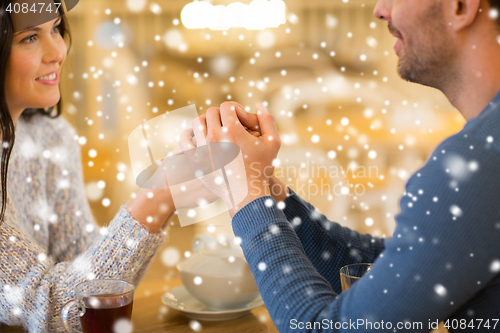 Image of happy couple with tea holding hands at restaurant