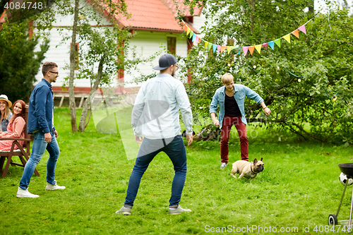 Image of happy friends playing with dog at summer garden