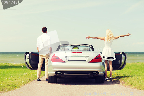 Image of happy man and woman near cabriolet car at sea